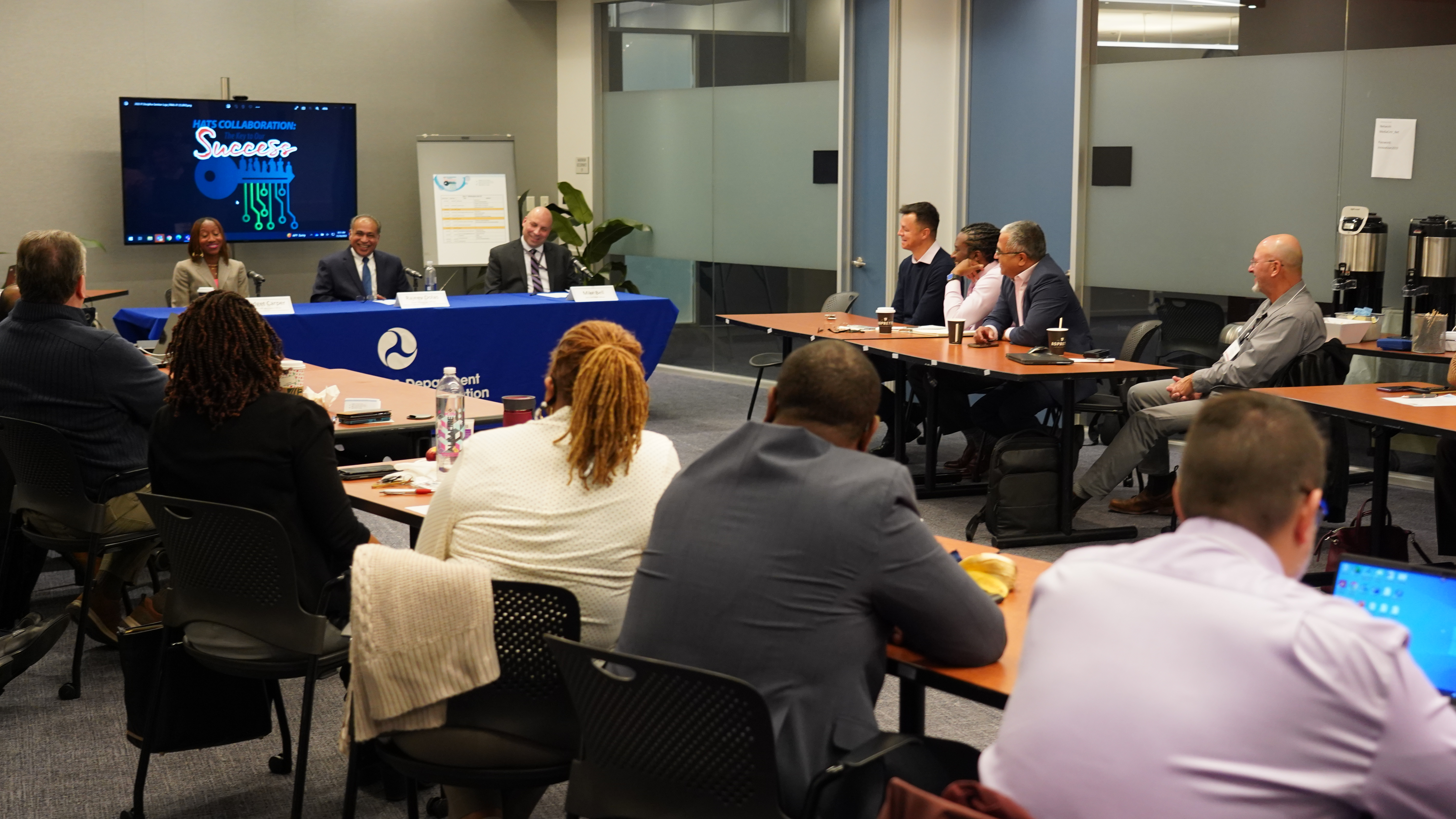 Attendees watching a panel of three speakers.